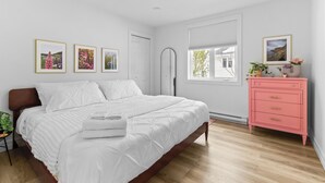 Une chambre à coucher avec un lit, une commode et trois tableaux encadrés accrochés au mur.