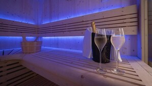 Eine Holzsauna mit Bänken, einem Eimer und zwei Sektgläsern.