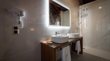 Un baño moderno con un espejo grande, dos lavamanos, un secador de pelo y una ducha.