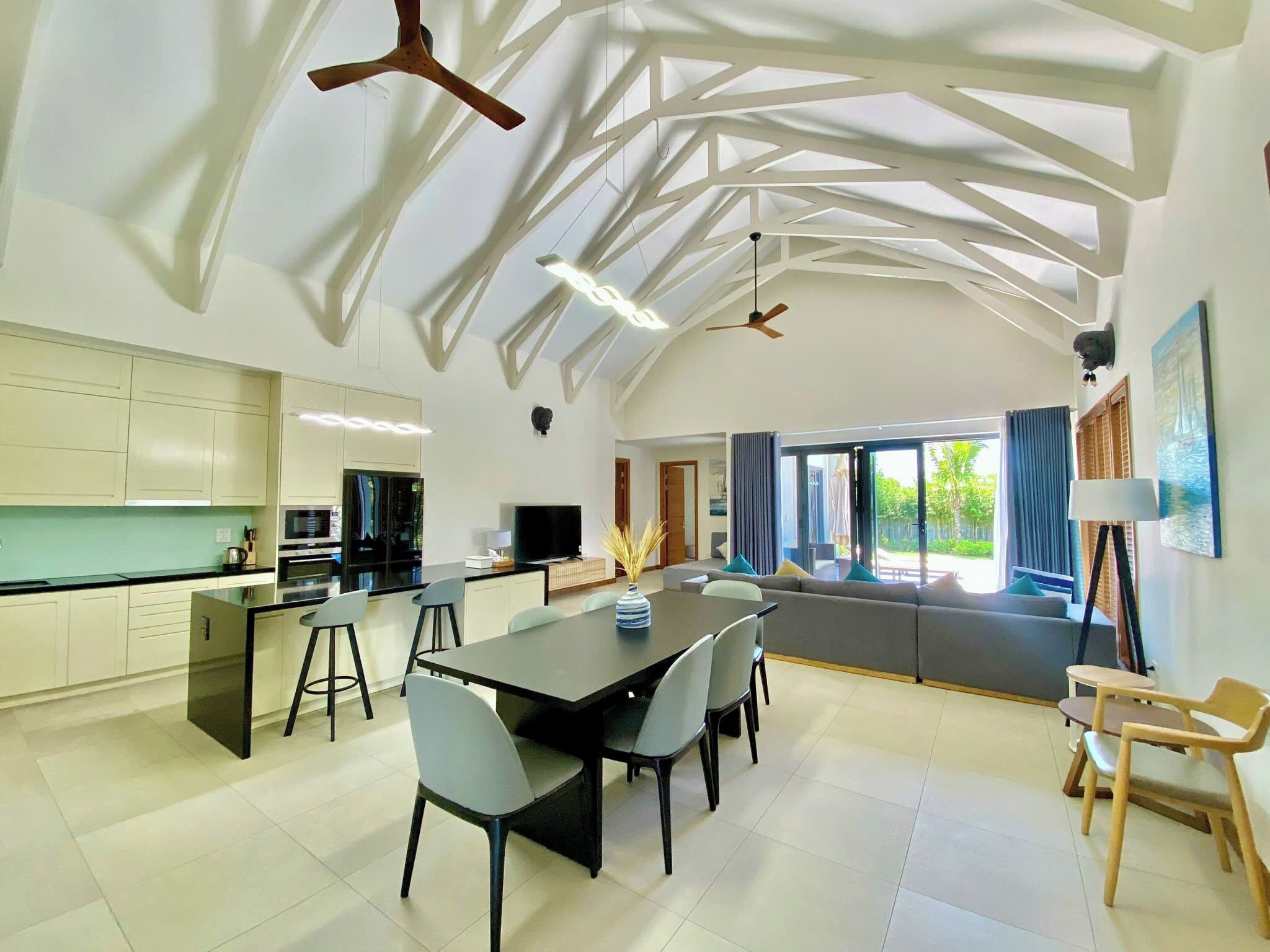 A modern kitchen with a dining area, a ceiling fan, and a large window.