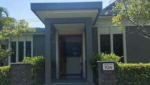 A modern house with a flat roof, a front porch, and a number sign indicating the address.