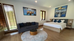 A modern bedroom with a bed, a sofa, a coffee table, and two paintings on the walls.