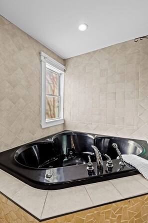 A modern bathroom with a freestanding bathtub, a window, and beige patterned tiles. - Colonial Row 3B, Off-Street Parking, Private Patio (St. John's)