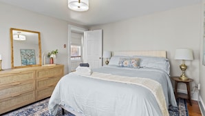 Une chambre à coucher avec un lit, une commode, un miroir et une table de chevet.