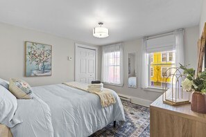 A bedroom with a bed, a bedside table, a window, and a painting on the wall. - Colonial Row 3B, Off-Street Parking, Private Patio (St. John's)