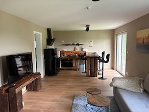 Un salon moderne avec un téléviseur, une table basse en bois et un canapé.