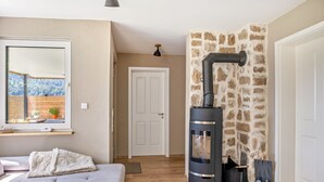 Habitació acollidora amb sofà, una llar de foc i finestra amb vista a una zona boscosa.