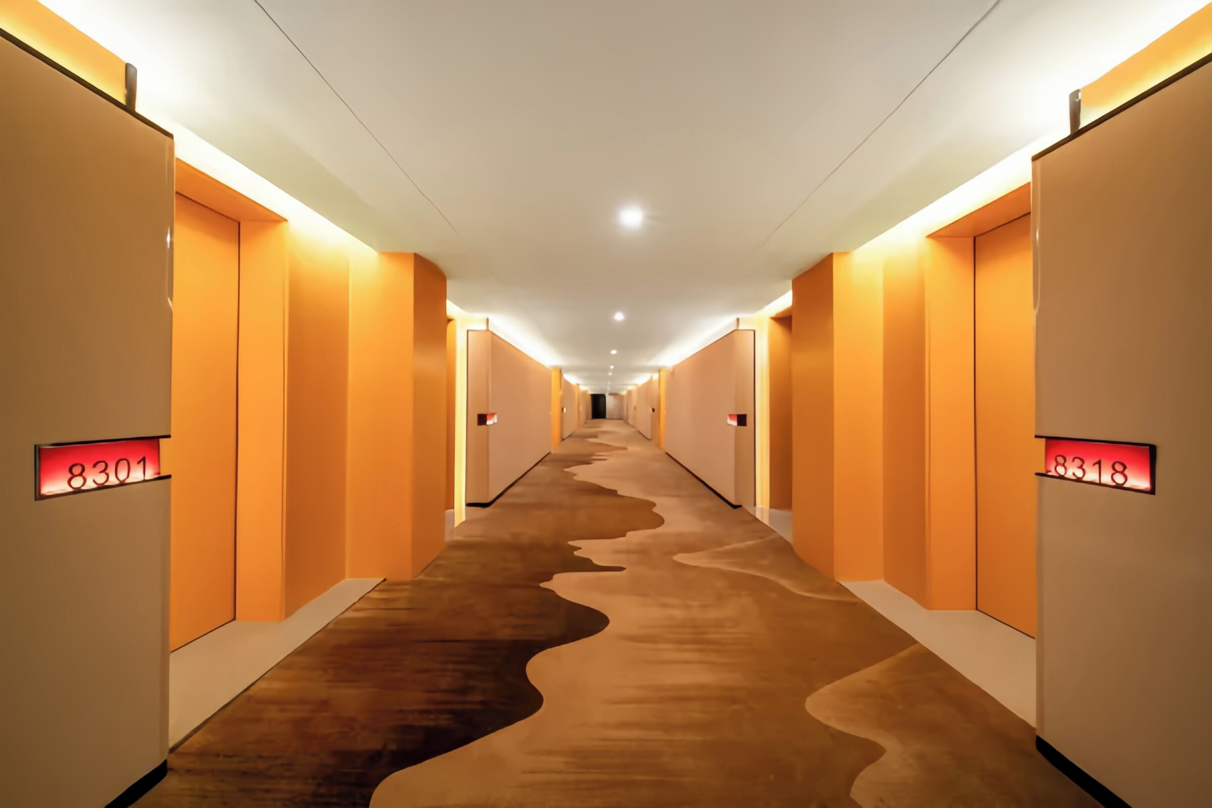 A long, narrow hallway with illuminated numbers on the walls, suggesting a hotel setting.