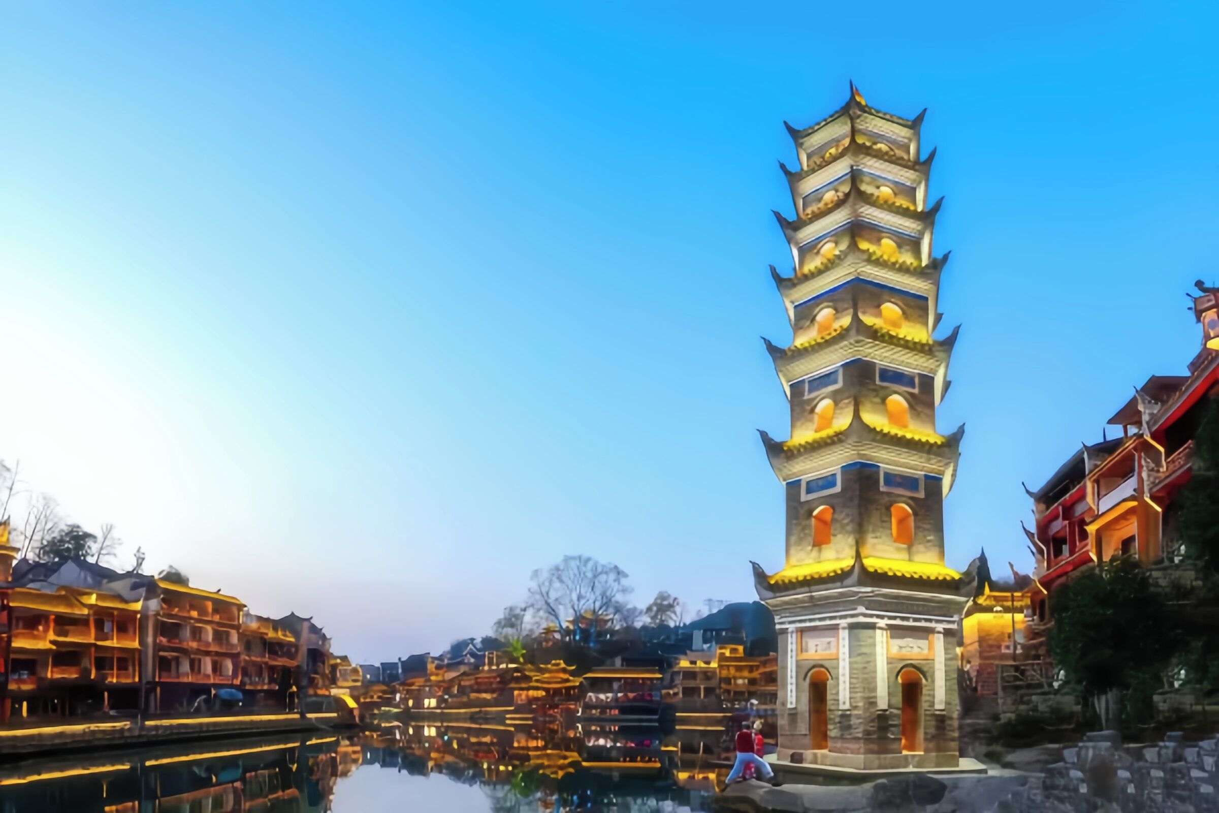 Una torre de estilo pagoda tradicional, con varios niveles, rodeada de edificios tradicionales a lo largo de un canal.