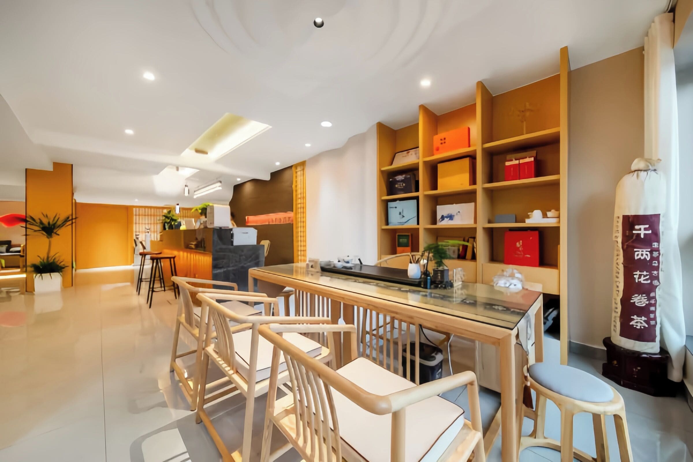 Un moderno vestíbulo de hotel con zona de comedor central, estanterías de madera con objetos y un gran pilar decorativo.