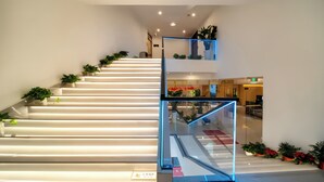 Een moderne trap met glazen leuning en potplanten.