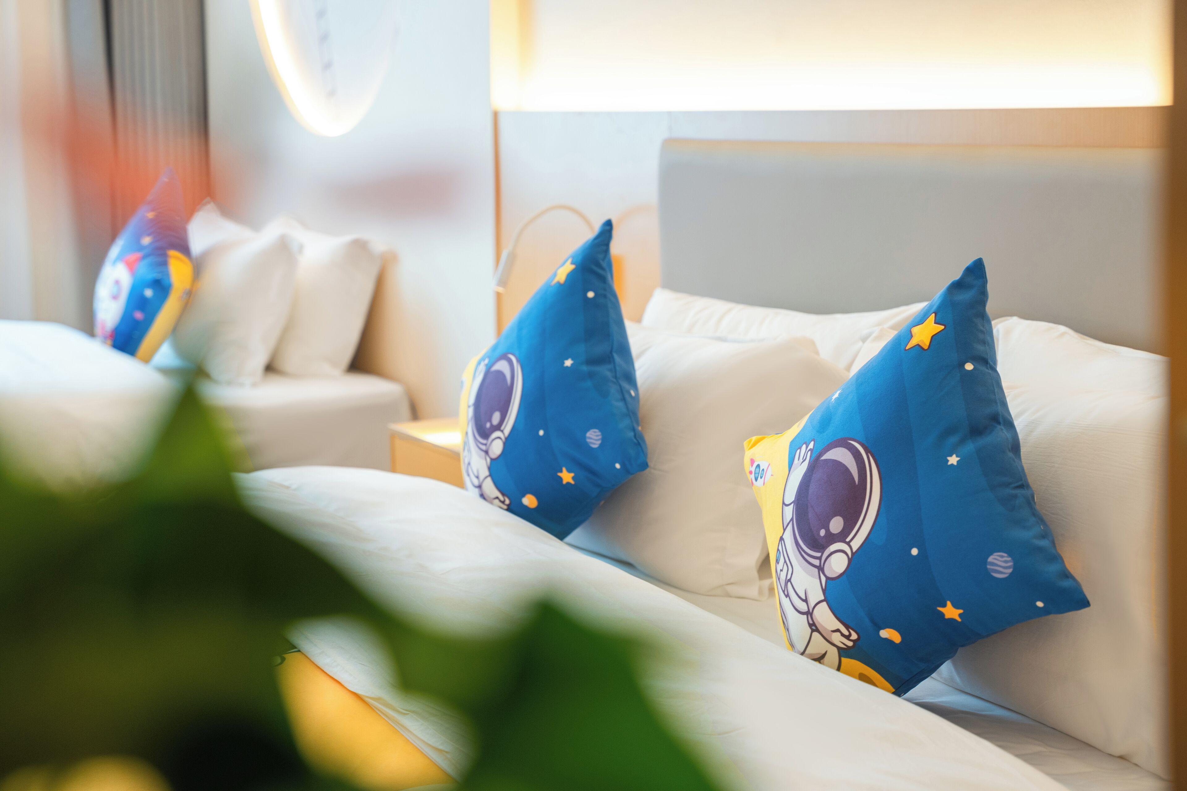 A hotel room with a bed, pillows, and a nightstand.