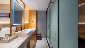 A modern bathroom with a large mirror, two sinks, a heated towel rail, and a glass shower enclosure.