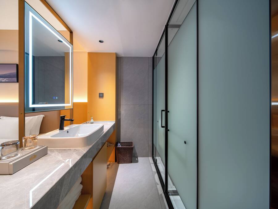 A modern bathroom with a large mirror, two sinks, a heated towel rail, and a glass shower enclosure.
