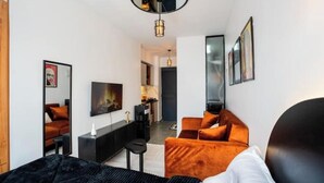 Moderni hotellihuone, jossa on sänky, työpöytä, tuoli ja sohva.