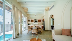 A spacious living area with a dining table, sofa, and kitchen in the background. - Staymaster White Castle-4BHK (Vagator)