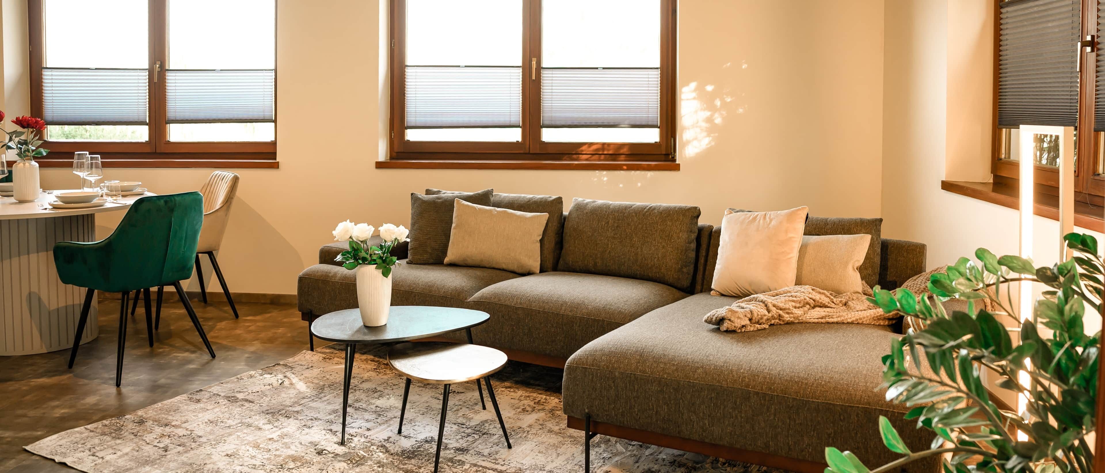 A living room with a sectional sofa, a round coffee table, and a dining area with a chair and table.