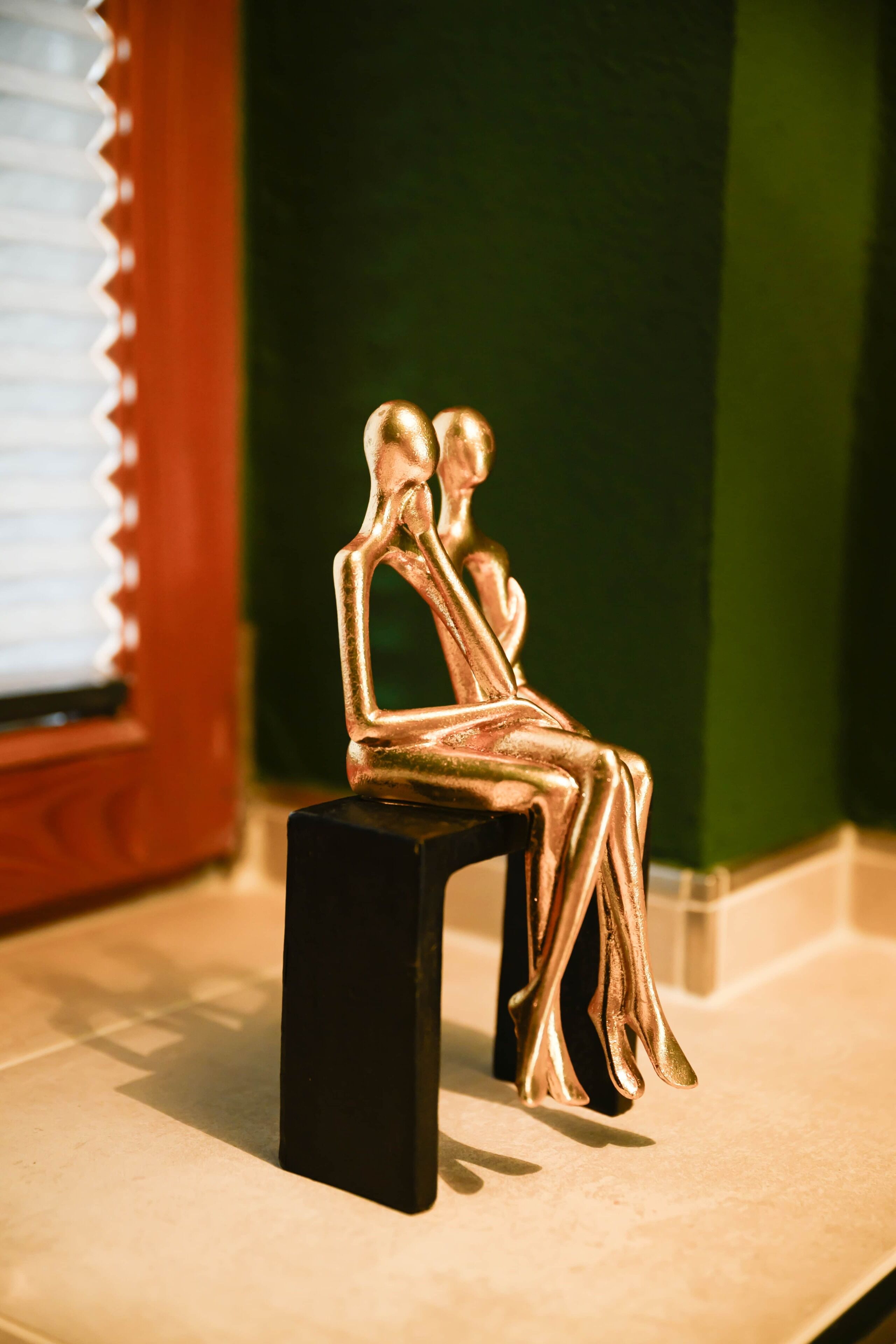 Un objeto pequeño y negro, rectangular, con una estatua dorada de dos figuras sentadas encima.