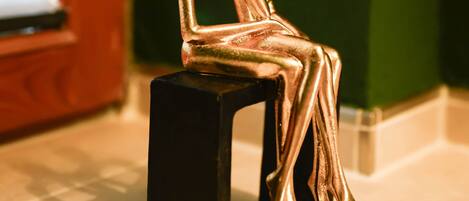 Un objeto pequeño y negro, rectangular, con una estatua dorada de dos figuras sentadas encima.