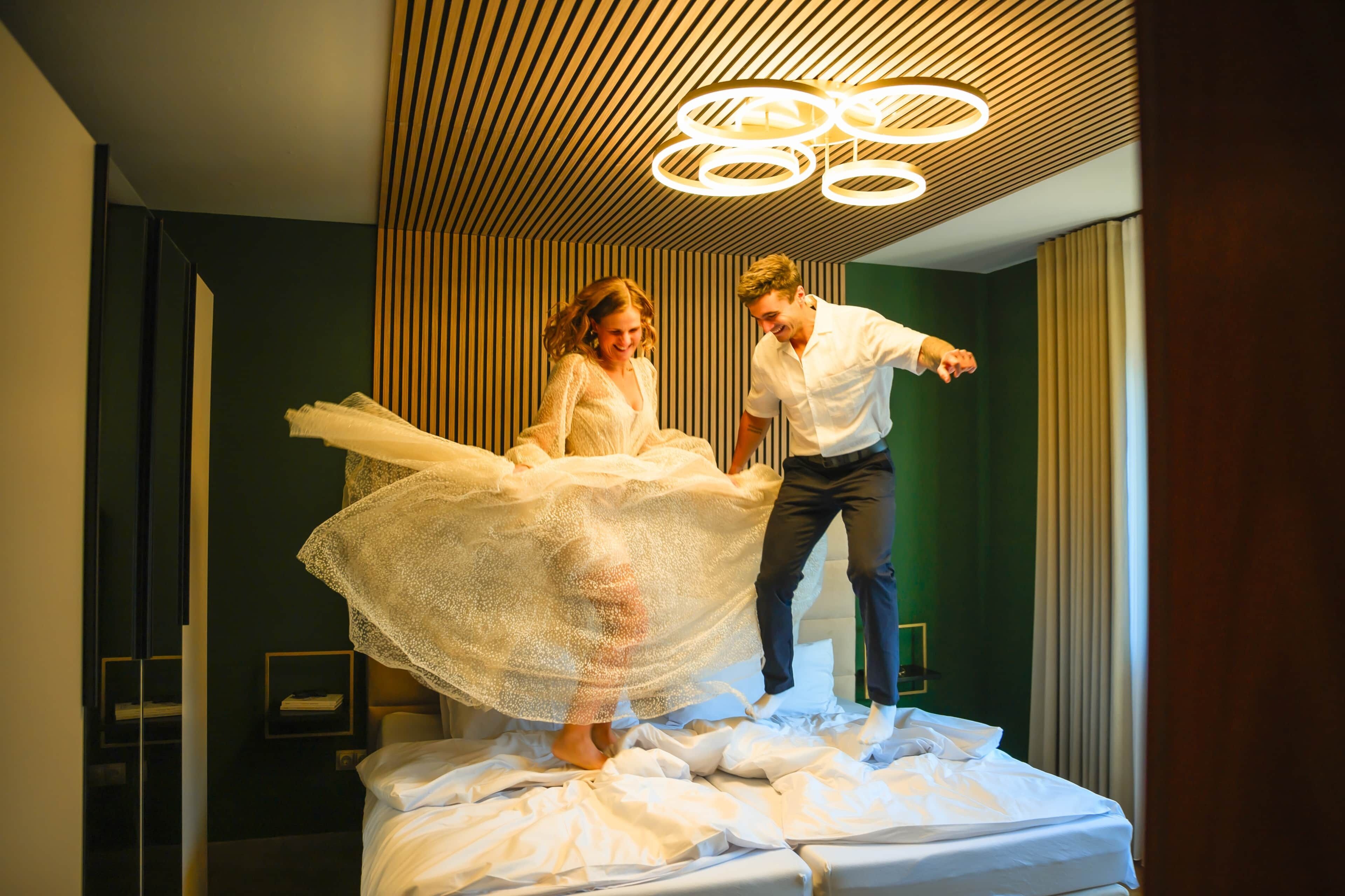 Une pièce comprenant un lit, un luminaire moderne au plafond et un mur recouvert de panneaux de bois verticaux.
