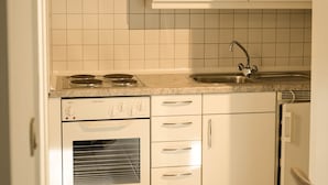 Cozinha com armários brancos, fogão, pia e máquina de lavar louça.