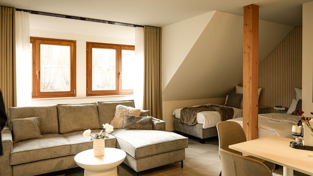A modern living room with a sofa, a coffee table, and a dining area. - SECHSER - Easy Apartment (Spalt)