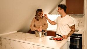 A kitchen with a marble countertop, a stainless steel pot, and a person holding a tomato. - DREIER - Cozy Apartment (Spalt)