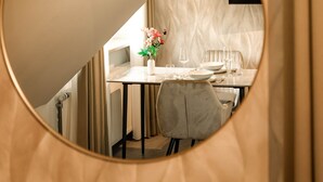 A circular mirror reflecting a dining area with a table set for two, a vase with flowers, and a chair. - DREIER - Cozy Apartment (Spalt)