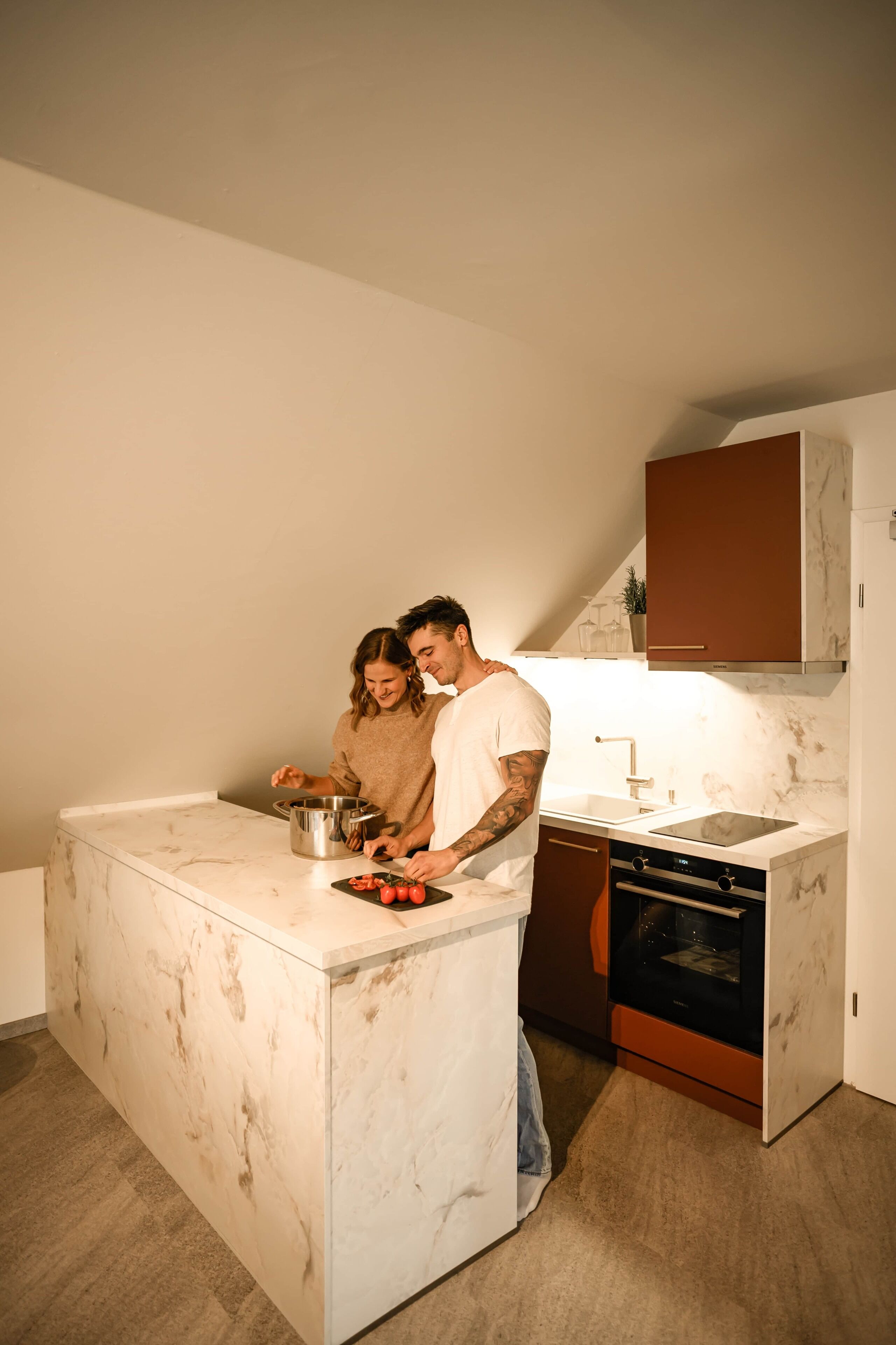 Cocina compacta con encimera de mármol, horno integrado y lavabo.