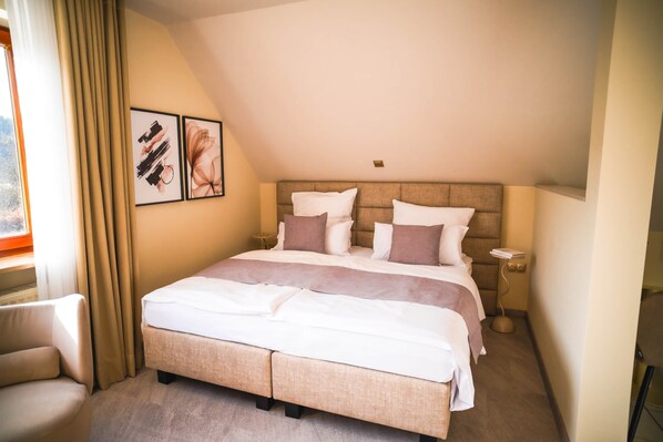 A hotel room with a large bed, a chair, and two framed pictures on the wall.