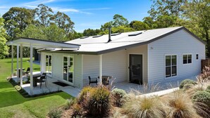 Ein eingeschossiges Haus mit überdachter Terrasse, Garage und einem kleinen Garten.