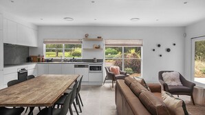 Eine moderne Küche mit Essbereich, einer Couch und Blick auf den Garten.