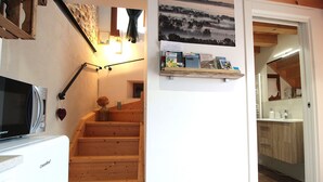 Eine Küche mit Mikrowelle, Kühlschrank, einer Holztreppe und einem Regal mit Büchern und einer Vase.