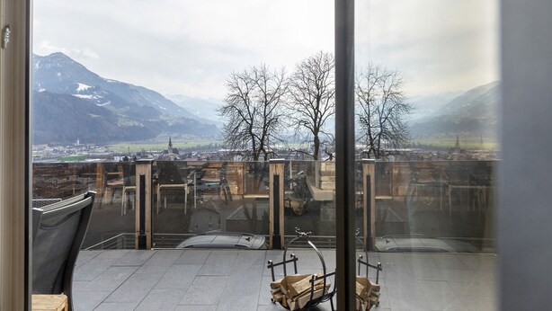 A balcony with a view of mountains, a chair, and a wooden bench. - Cozy Apartment Above the Rooftops of Jenbach (Jenbach)
