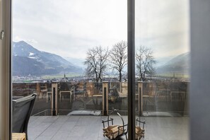 A balcony with a view of mountains, a chair, and a wooden bench. - Cozy Apartment Above the Rooftops of Jenbach (Jenbach)