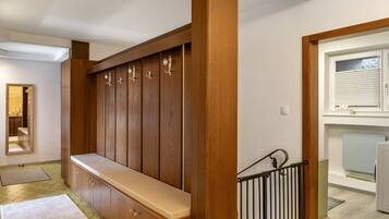 A wooden bench with storage cabinets, a mirror, and a staircase with a metal railing.