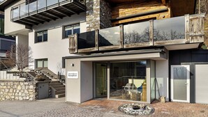 A modern building with a stone facade, a glass entrance, and a wooden balcony. - Cozy Apartment Above the Rooftops of Jenbach (Jenbach)