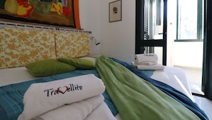 Camera d'albergo con un letto, cuscini verdi, una coperta e asciugamani con il marchio 'Trattellito'.