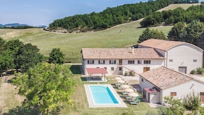 Una villa con piscina, porche cubierto y un granero.