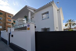 A white building with a balcony, a sign for a hotel, and a palm tree in the background. - Villa Lucia by WonderStays (Málaga)
