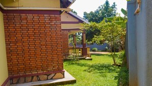 Un edificio de ladrillo con un patio techado, un pequeño jardín y un árbol.