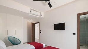 A modern hotel room with two beds, a ceiling fan, an air conditioning unit, a television, and a wardrobe. - O-Cyanea Villa: Luxurious 4-Bedroom Retreat with Heated Pool in Kournas (Paralia Kourna)