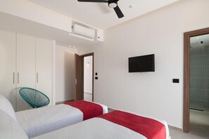 Ein modernes Hotelzimmer mit zwei Betten, einem Deckenventilator, einer Klimaanlage, einem Fernseher und einem Kleiderschrank.