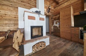 Ein rustikales Blockhaus-Interieur mit Kamin, Holzwänden und einem aufgehängten Hirschkopf.