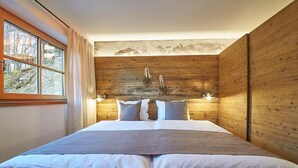 Ein Schlafzimmer mit einem großen Bett, Holzwänden und Blick auf die Berge durch ein Fenster.