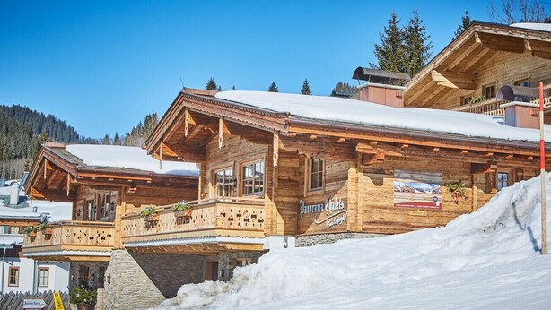 Eine Holzhütte mit Balkon, schneebedecktem Dach und einem Schild, das das 'Panorama Hotel' bewirbt.