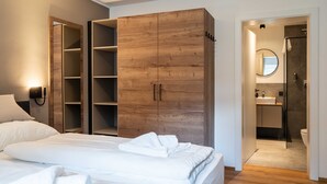Una camera da letto con un letto, un armadio in legno e un bagno con doccia e WC.