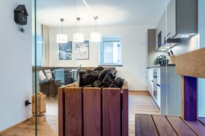 Une cuisine moderne avec des meubles en bois, un four encastré et un coin repas séparé par une cloison en verre.