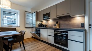 Una cucina moderna con elettrodomestici integrati, una zona pranzo con tavolo e sedie, e una finestra con vista su un edificio.