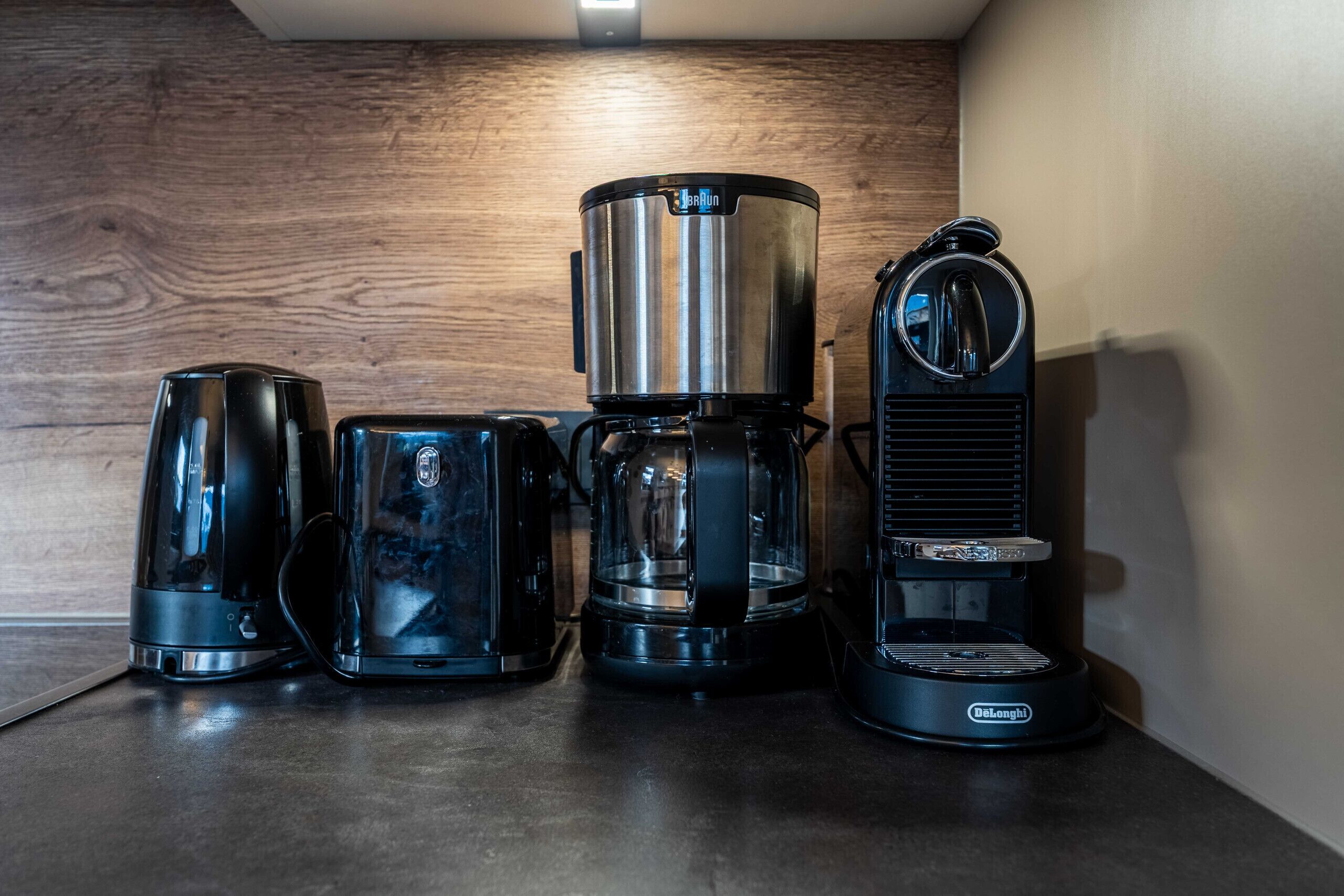 Kaffemaskine, elkedel og kaffekande på en bordplade.